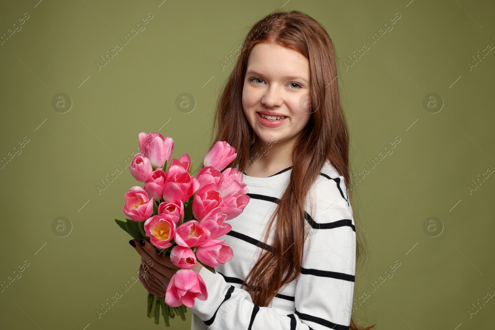 Photo of Beautiful teenage girl with bouquet of tulips on olive background