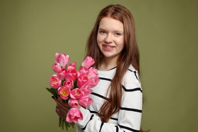 Photo of Beautiful teenage girl with bouquet of tulips on olive background