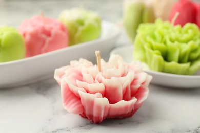 Photo of Beautiful flower shaped candles on white marble background, closeup