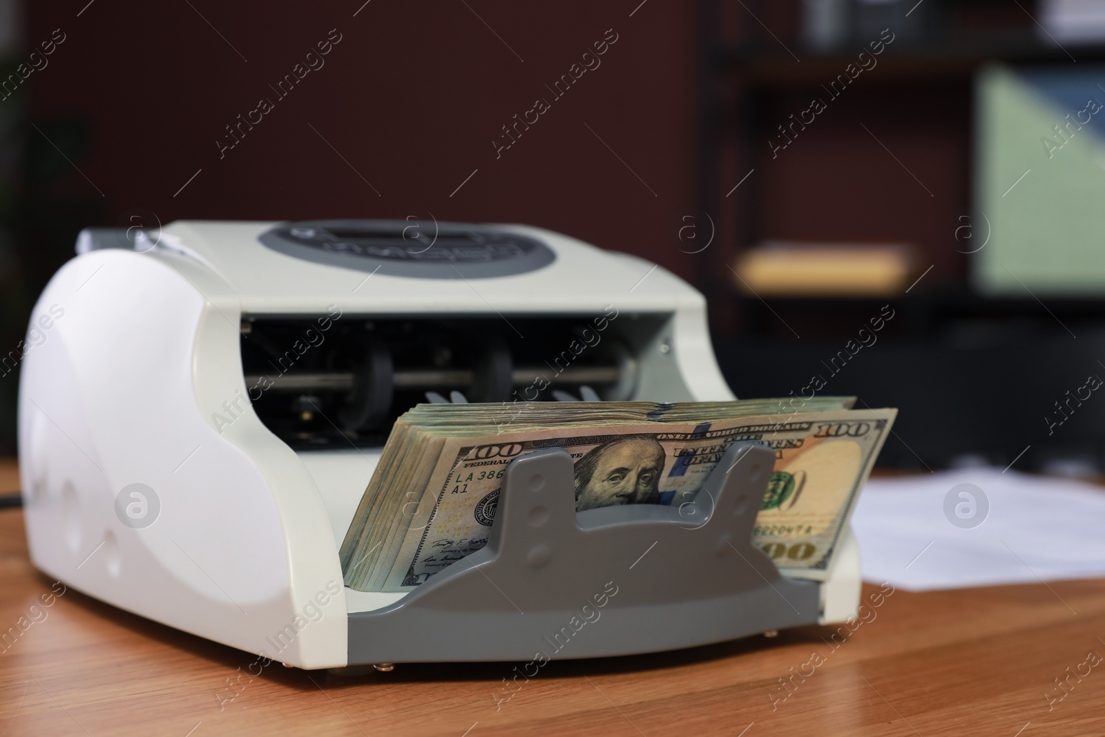 Photo of Modern banknote counter with money on wooden table indoors, closeup