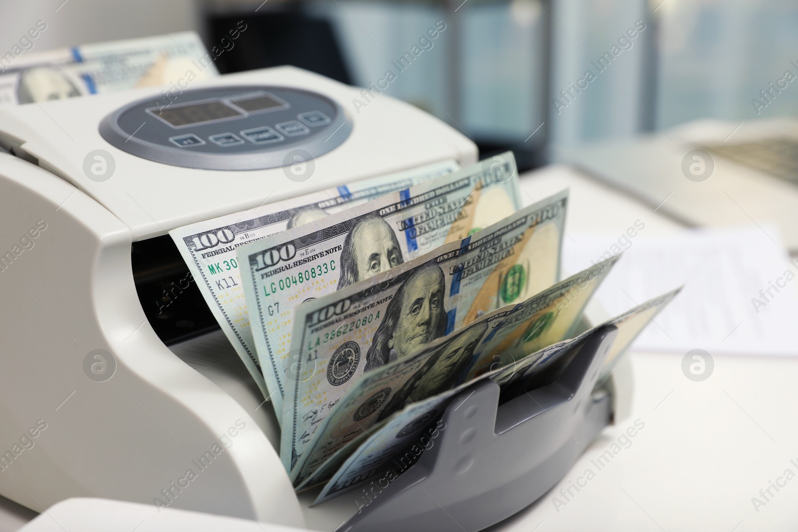 Photo of Modern banknote counter with money on white table indoors, closeup