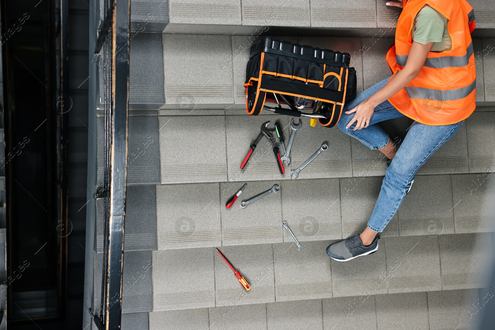 Photo of Accident at work. Injured woman and toolkit on stairs indoors, above view. Space for text