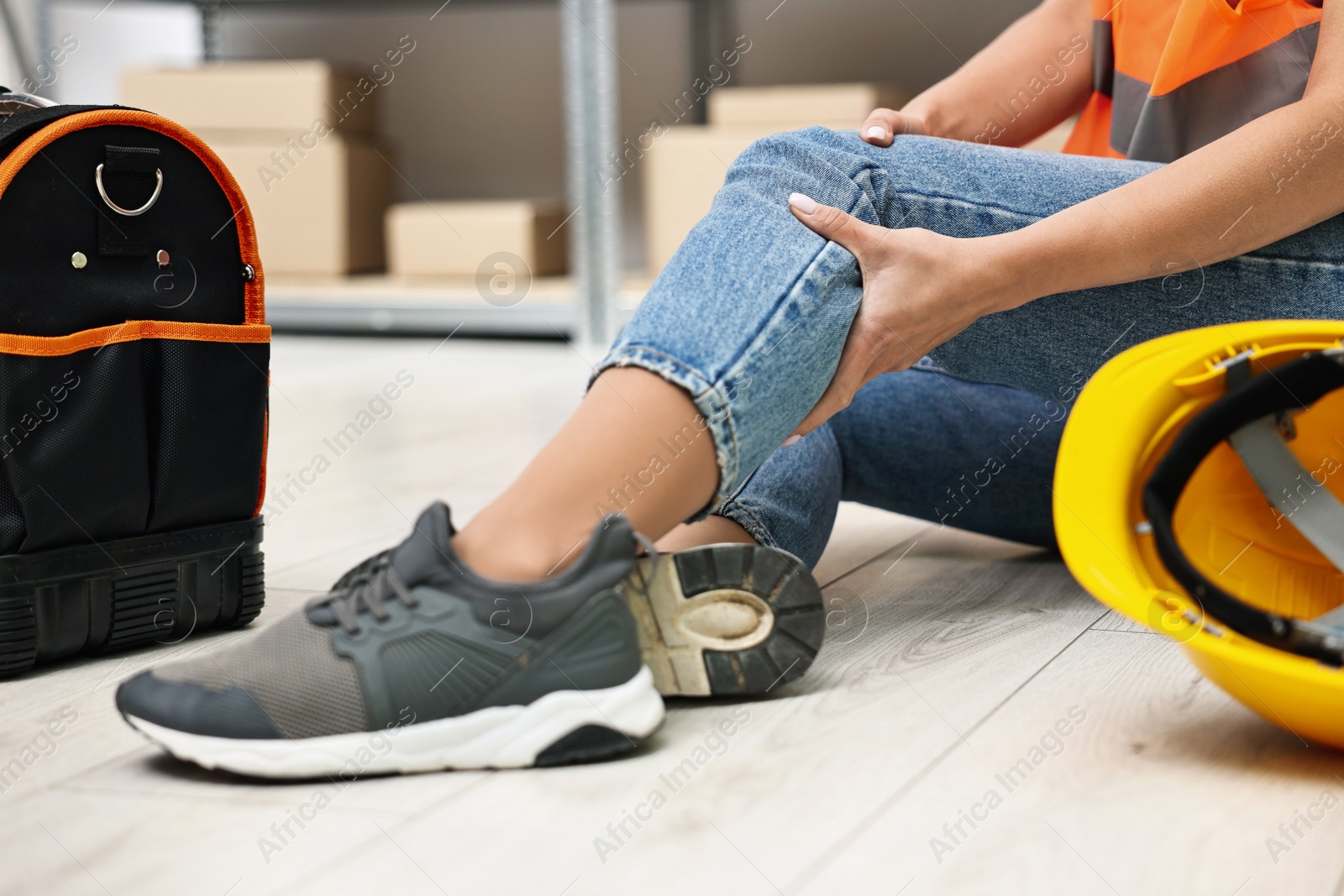 Photo of Accident at work. Woman with injured leg on floor indoors, closeup