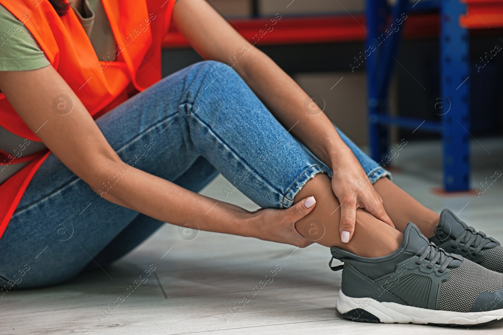 Photo of Accident at work. Woman with injured leg on floor indoors, closeup