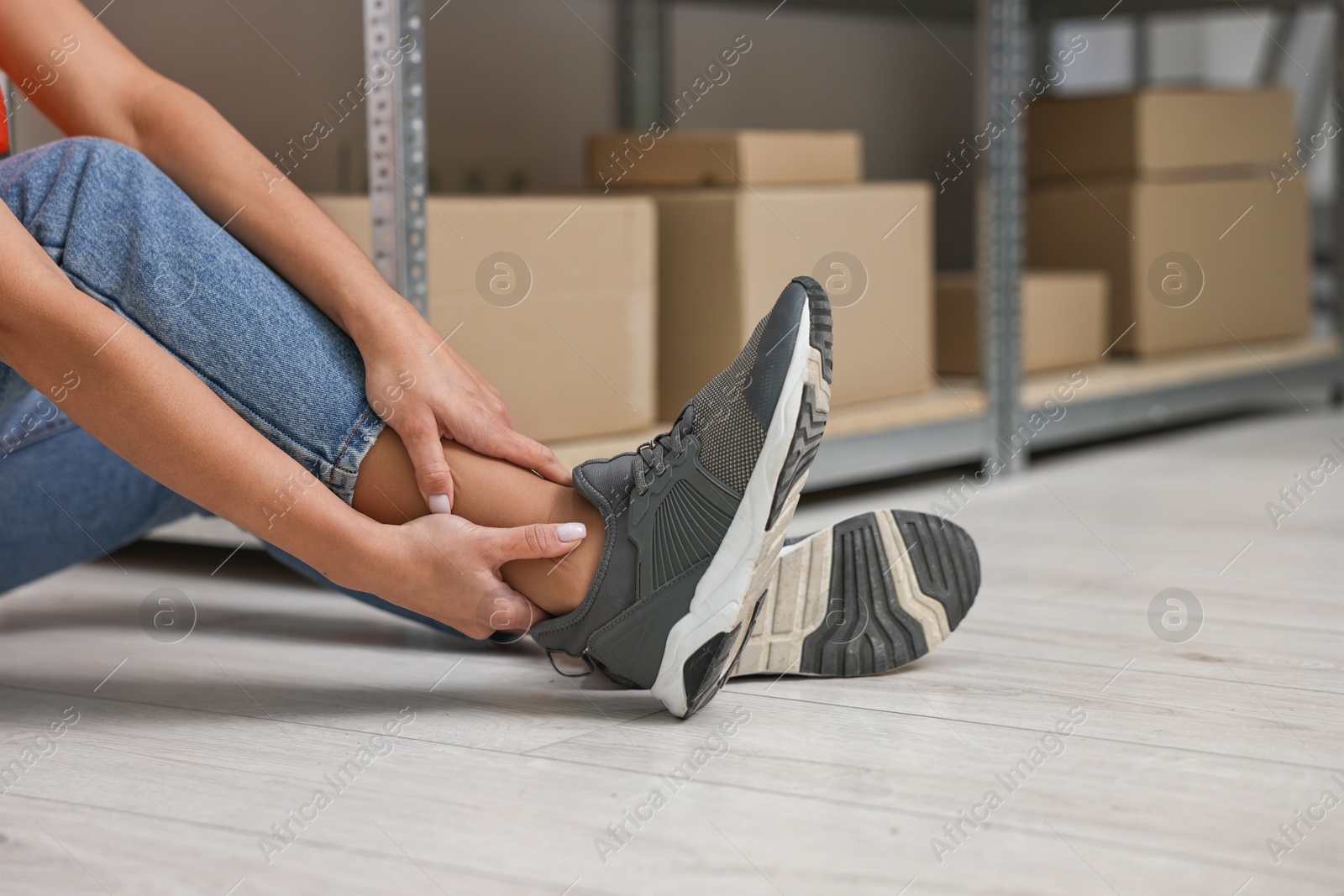 Photo of Accident at work. Woman with injured leg on floor indoors, closeup