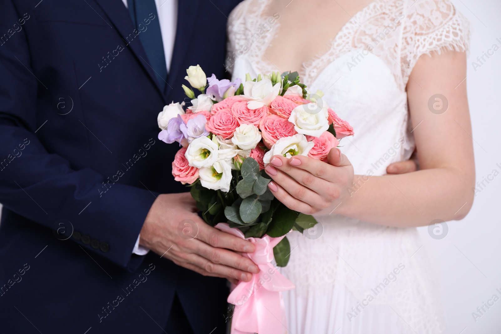 Photo of Bride with beautiful wedding bouquet and groom on light background, closeup