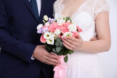 Photo of Bride with beautiful wedding bouquet and groom on light background, closeup