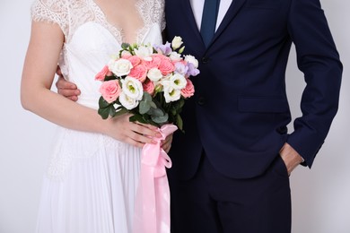 Photo of Bride with beautiful wedding bouquet and groom on light background, closeup