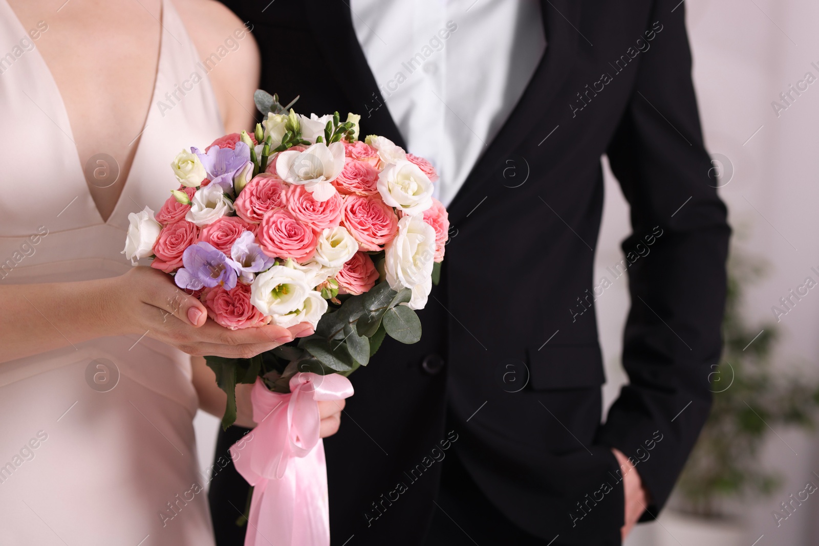 Photo of Bride with beautiful wedding bouquet and groom indoors, closeup