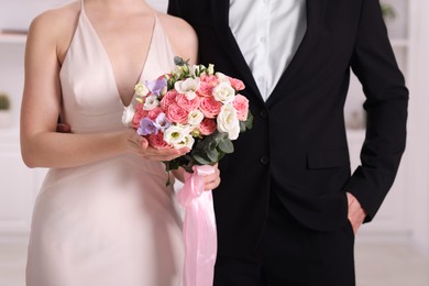 Photo of Bride with beautiful wedding bouquet and groom indoors, closeup