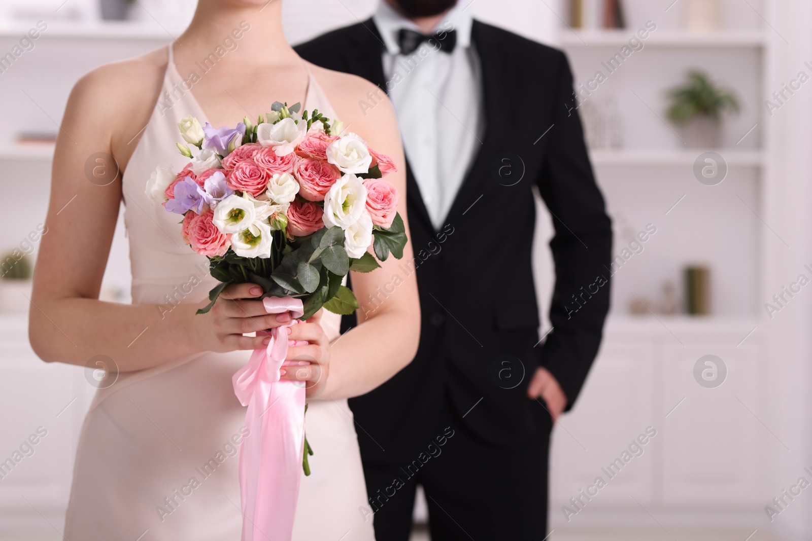 Photo of Bride with beautiful wedding bouquet and groom indoors, closeup