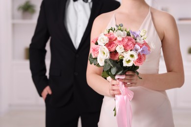 Photo of Bride with beautiful wedding bouquet and groom indoors, closeup