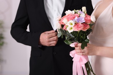 Photo of Bride with beautiful wedding bouquet and groom indoors, closeup