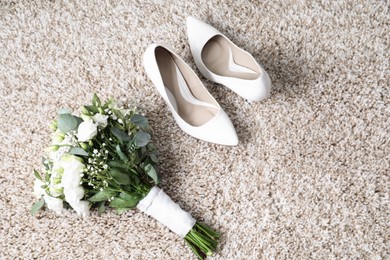 Photo of Wedding bouquet of beautiful flowers and bridal shoes on beige carpet, top view