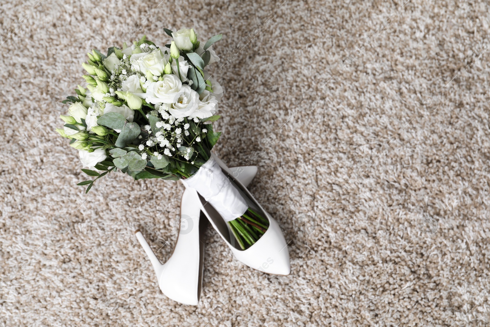 Photo of Wedding bouquet of beautiful flowers and bridal shoes on beige carpet, top view. Space for text