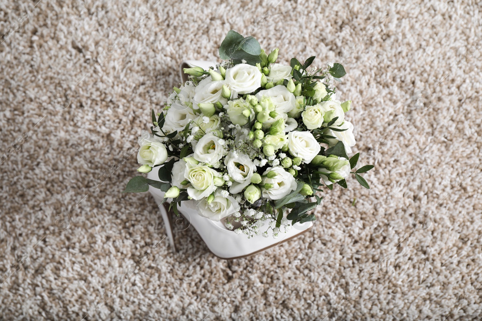 Photo of Wedding bouquet of beautiful flowers and bridal shoe on beige carpet, top view