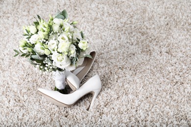 Photo of Wedding bouquet of beautiful flowers and bridal shoes on beige carpet. Space for text