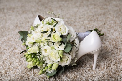 Photo of Wedding bouquet of beautiful flowers and bridal shoes on beige carpet, closeup