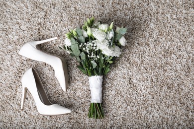 Photo of Wedding bouquet of beautiful flowers and bridal shoes on beige carpet, top view. Space for text