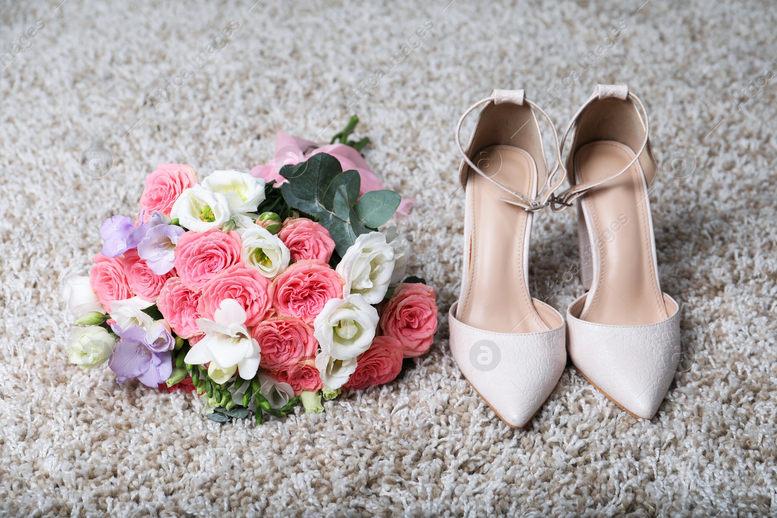 Photo of Wedding bouquet of beautiful flowers and bridal shoes on beige carpet