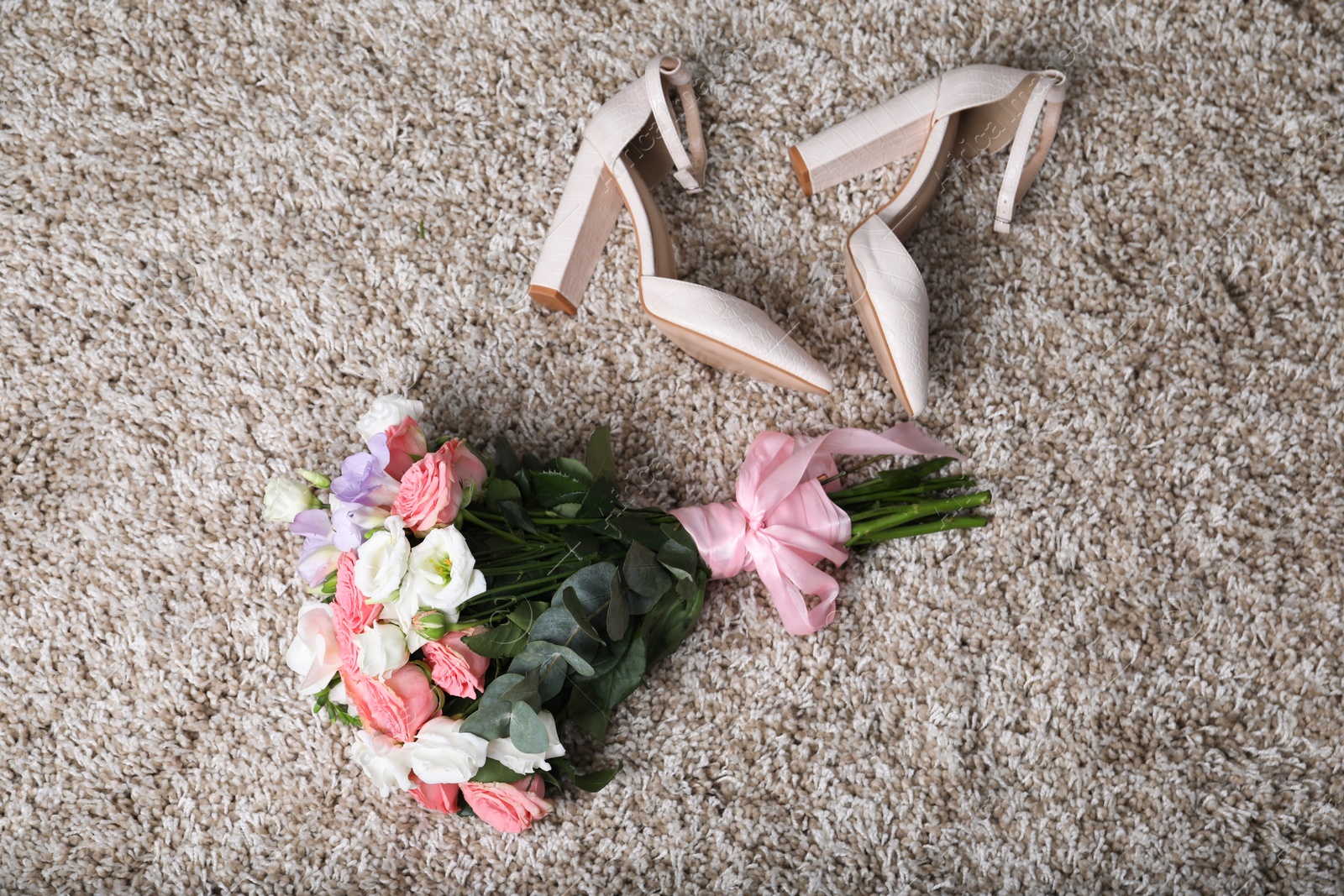 Photo of Wedding bouquet of beautiful flowers and bridal shoes on beige carpet, top view