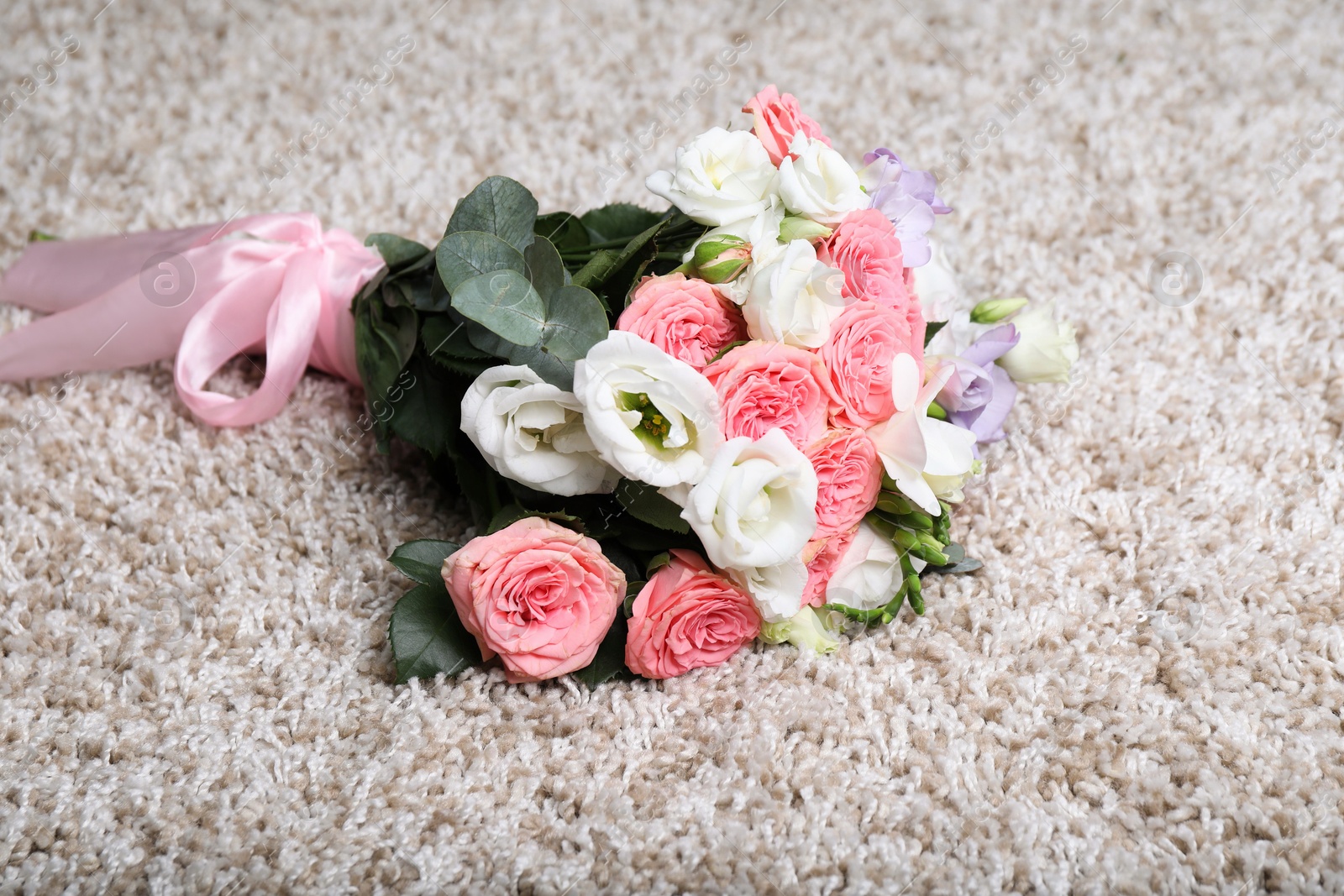 Photo of Wedding bouquet of beautiful flowers on beige carpet, closeup