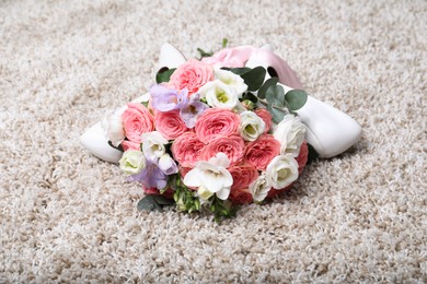 Photo of Wedding bouquet of beautiful flowers and bridal shoes on beige carpet