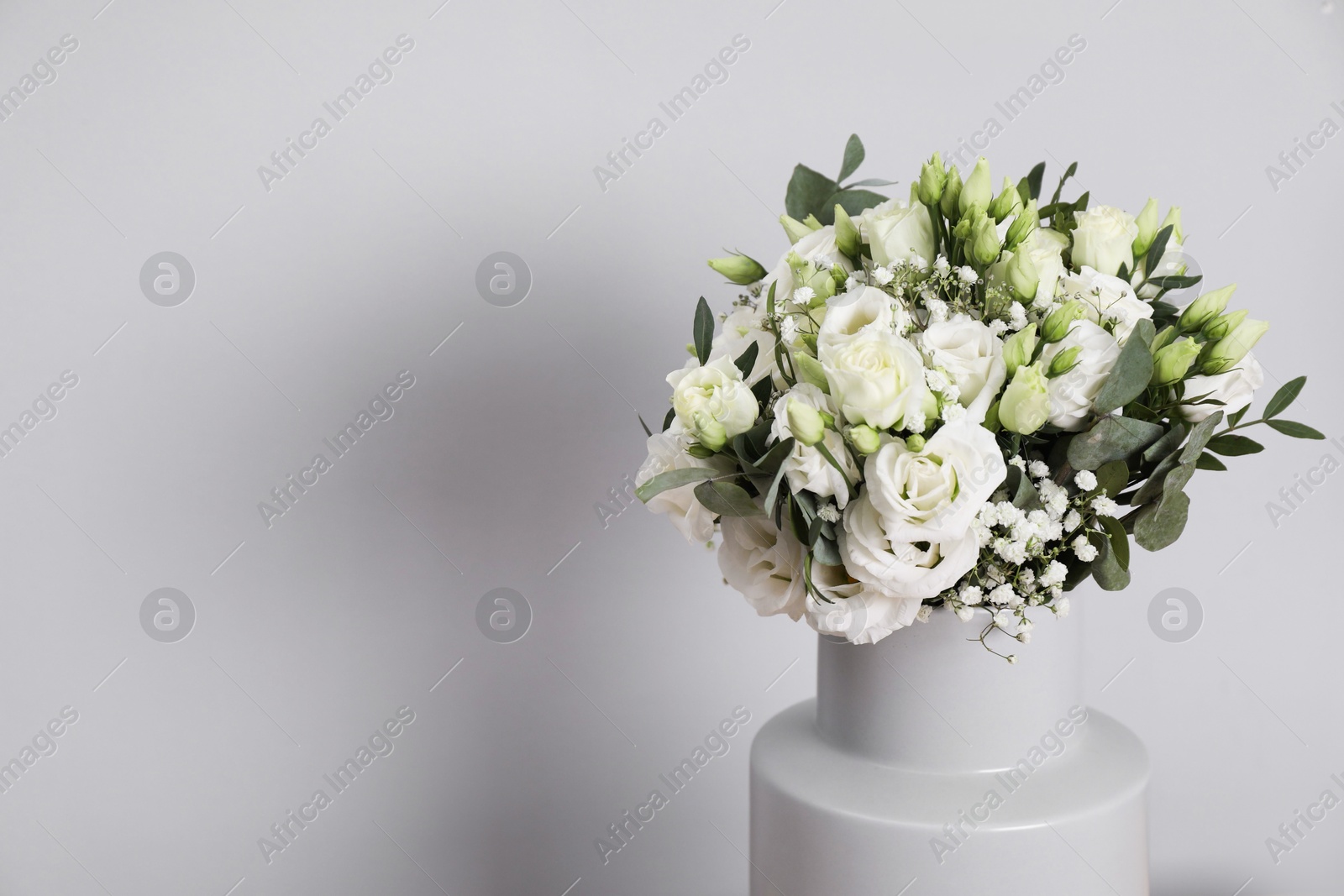 Photo of Wedding bouquet of beautiful flowers in vase against grey wall, closeup. Space for text