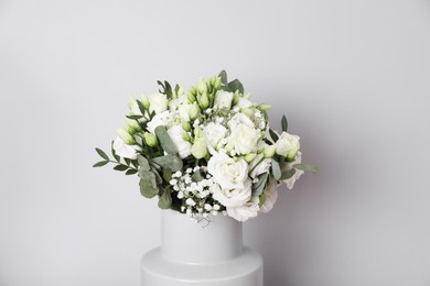 Photo of Wedding bouquet of beautiful flowers in vase against grey wall, closeup