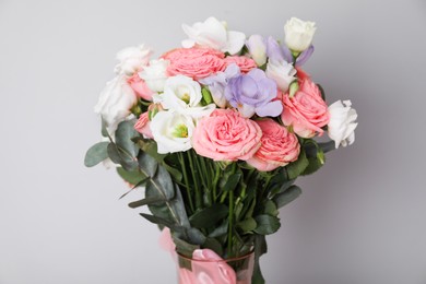 Photo of Wedding bouquet of beautiful flowers in vase against grey wall, closeup