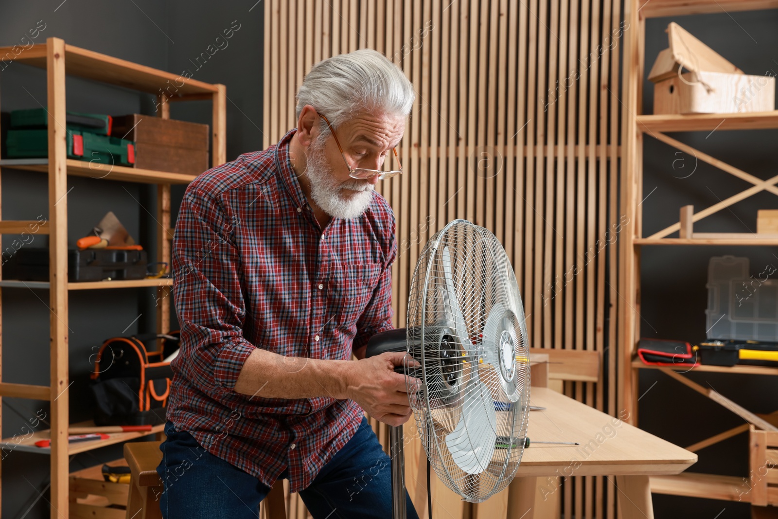 Photo of Relaxing hobby. Senior man repairing fan in workshop