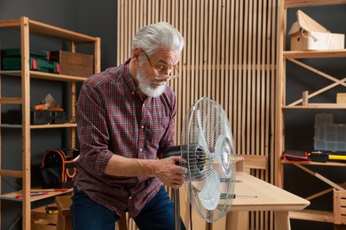 Photo of Relaxing hobby. Senior man repairing fan in workshop