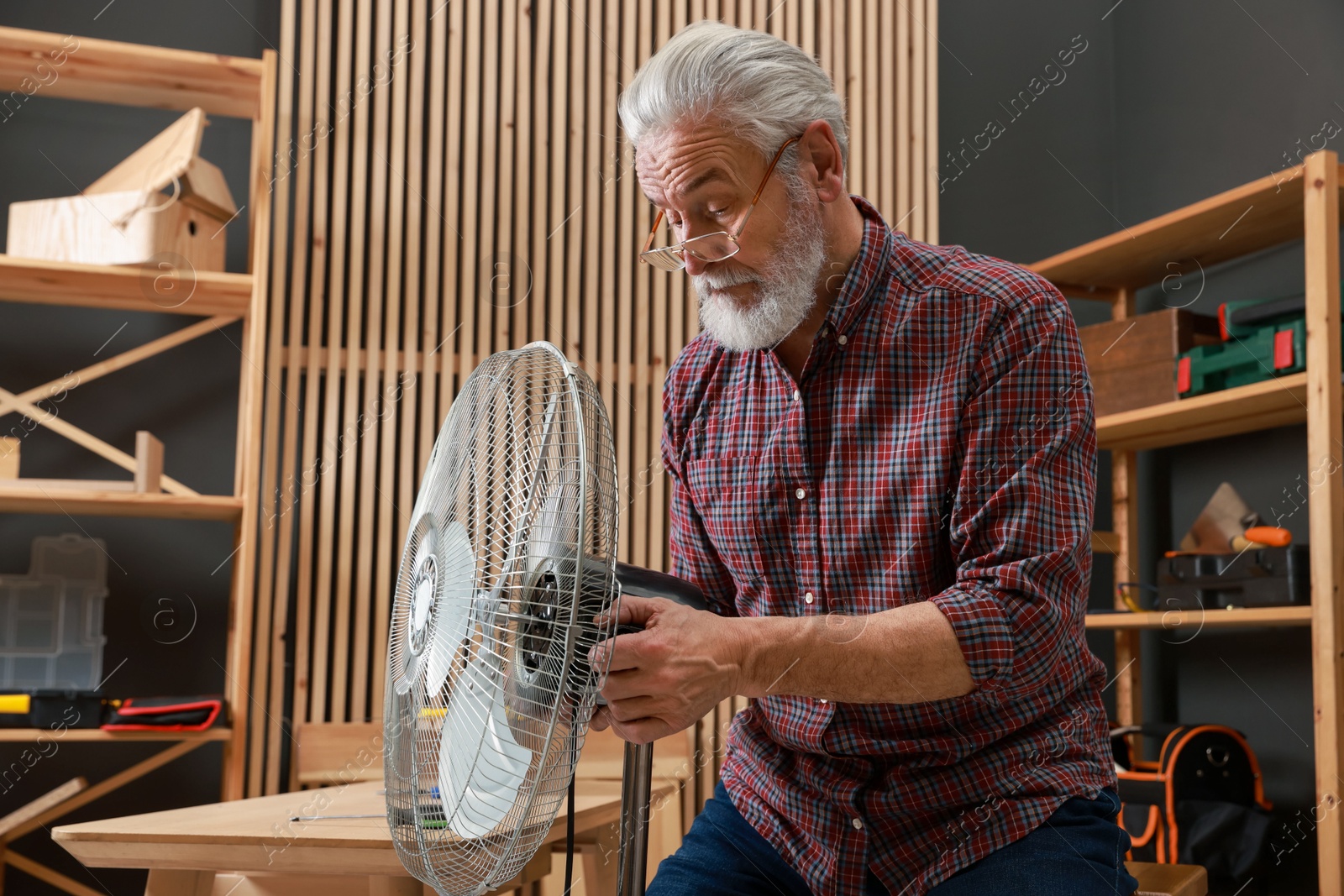 Photo of Relaxing hobby. Senior man repairing fan in workshop