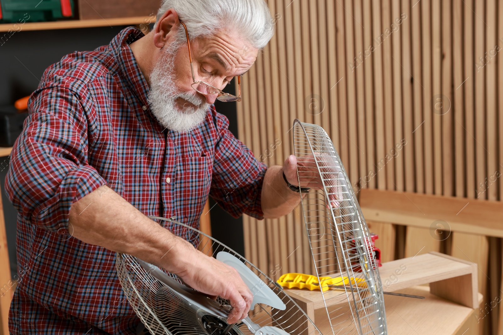 Photo of Relaxing hobby. Senior man repairing fan in workshop