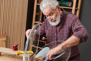 Photo of Relaxing hobby. Senior man repairing fan in workshop