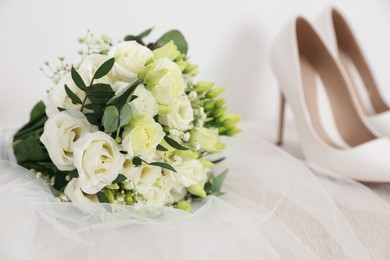 Photo of Beautiful wedding bouquet, veil and bridal shoes on light background, closeup