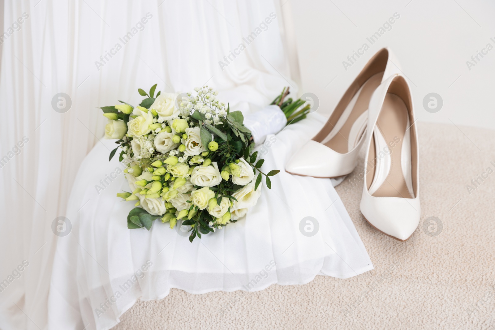 Photo of Beautiful wedding bouquet, bridal shoes and dress against light background