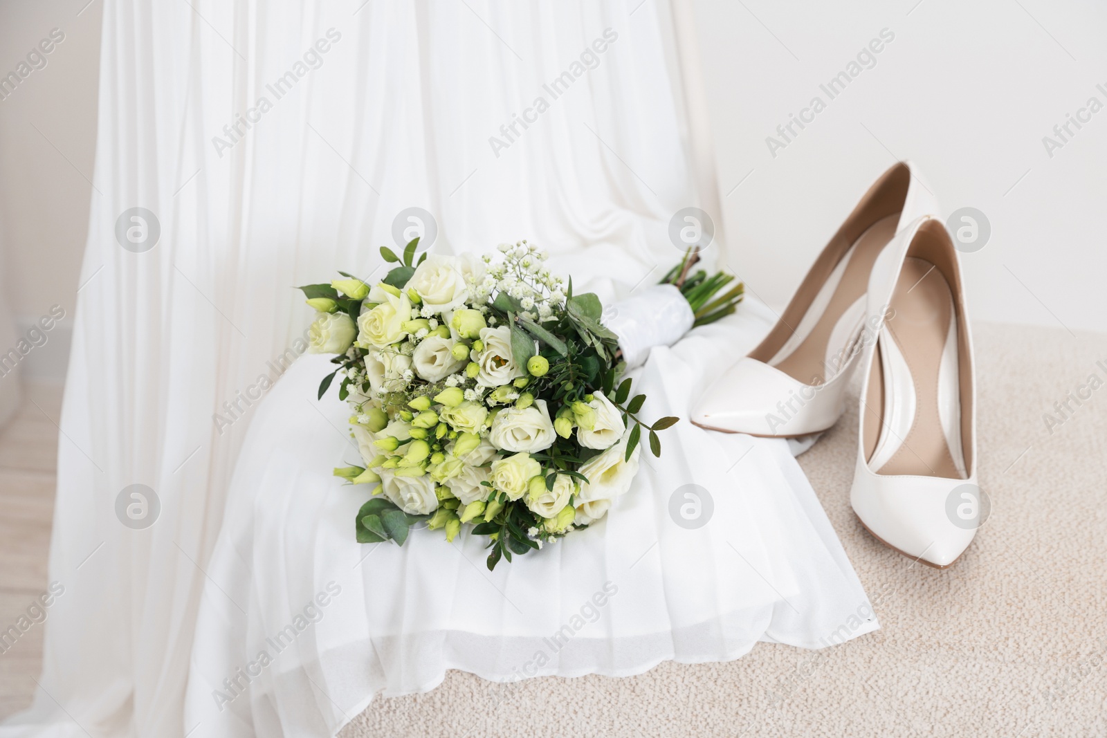 Photo of Beautiful wedding bouquet, bridal shoes and dress against light background