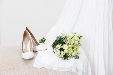 Photo of Beautiful wedding bouquet, bridal shoes and dress against light background