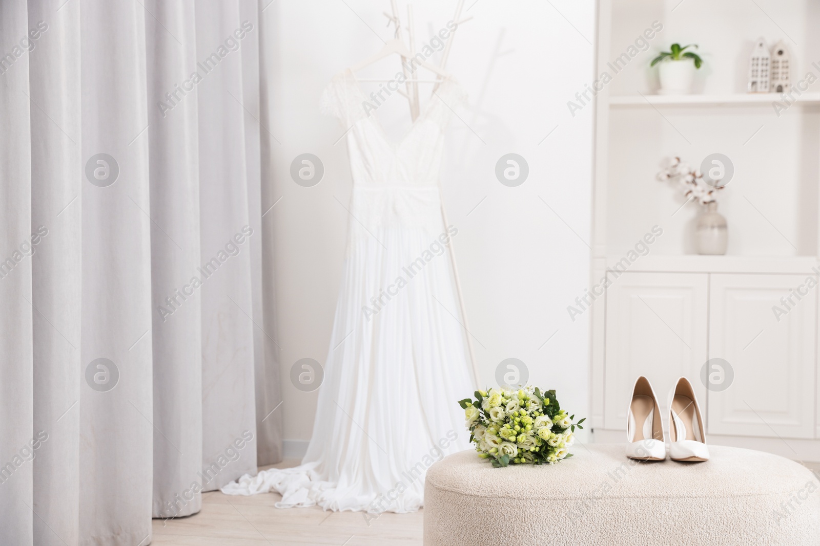 Photo of Beautiful wedding bouquet and bridal shoes on pouf indoors