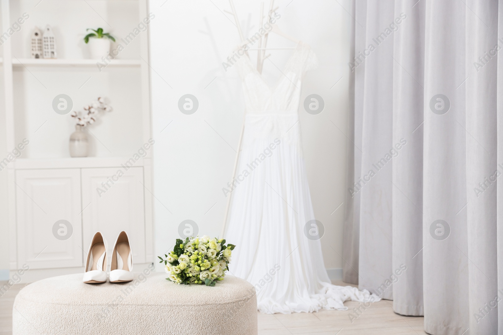 Photo of Beautiful wedding bouquet and bridal shoes on pouf indoors