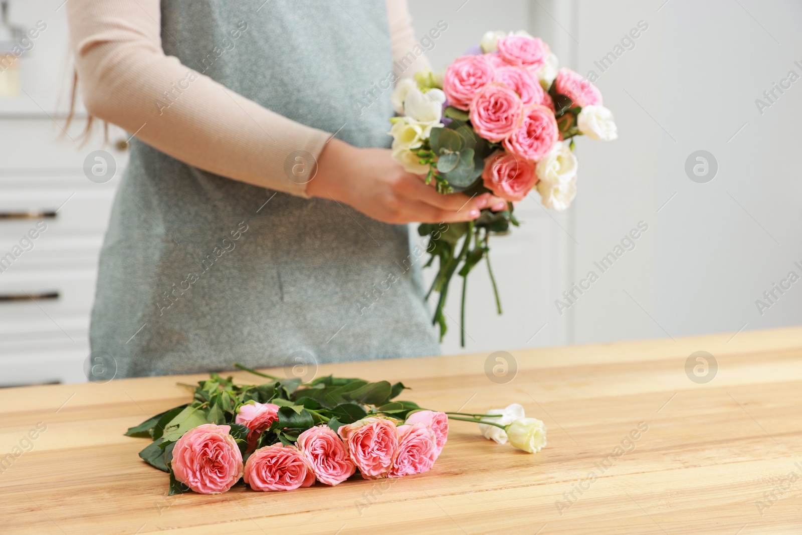 Photo of Florist making beautiful wedding bouquet at wooden table indoors, closeup