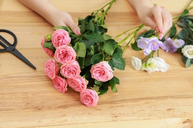 Photo of Florist making beautiful wedding bouquet at wooden table, closeup