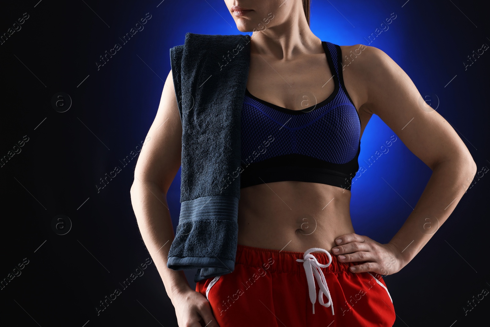 Photo of Sporty woman with terry towel on dark blue background, closeup