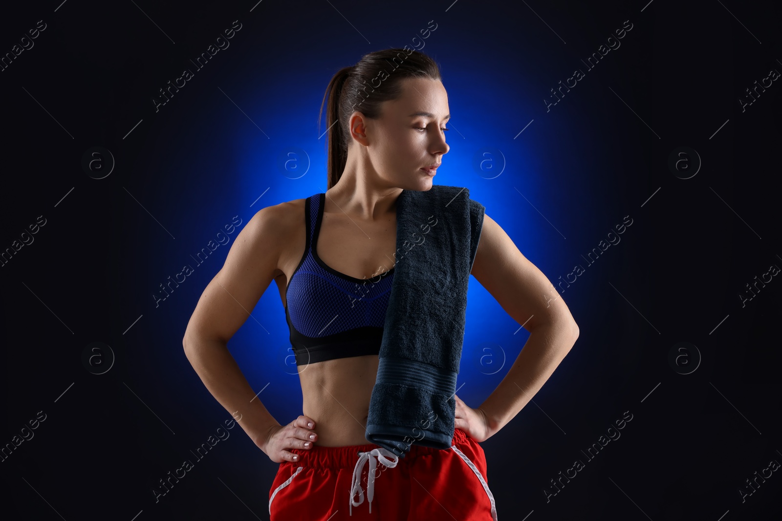 Photo of Sporty woman with terry towel on dark blue background