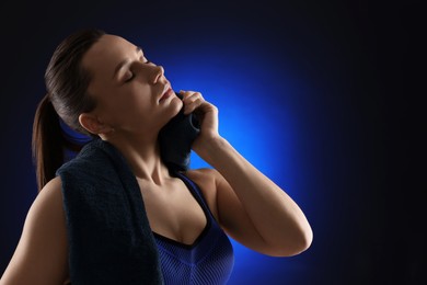 Photo of Sporty woman with terry towel on dark blue background. Space for text