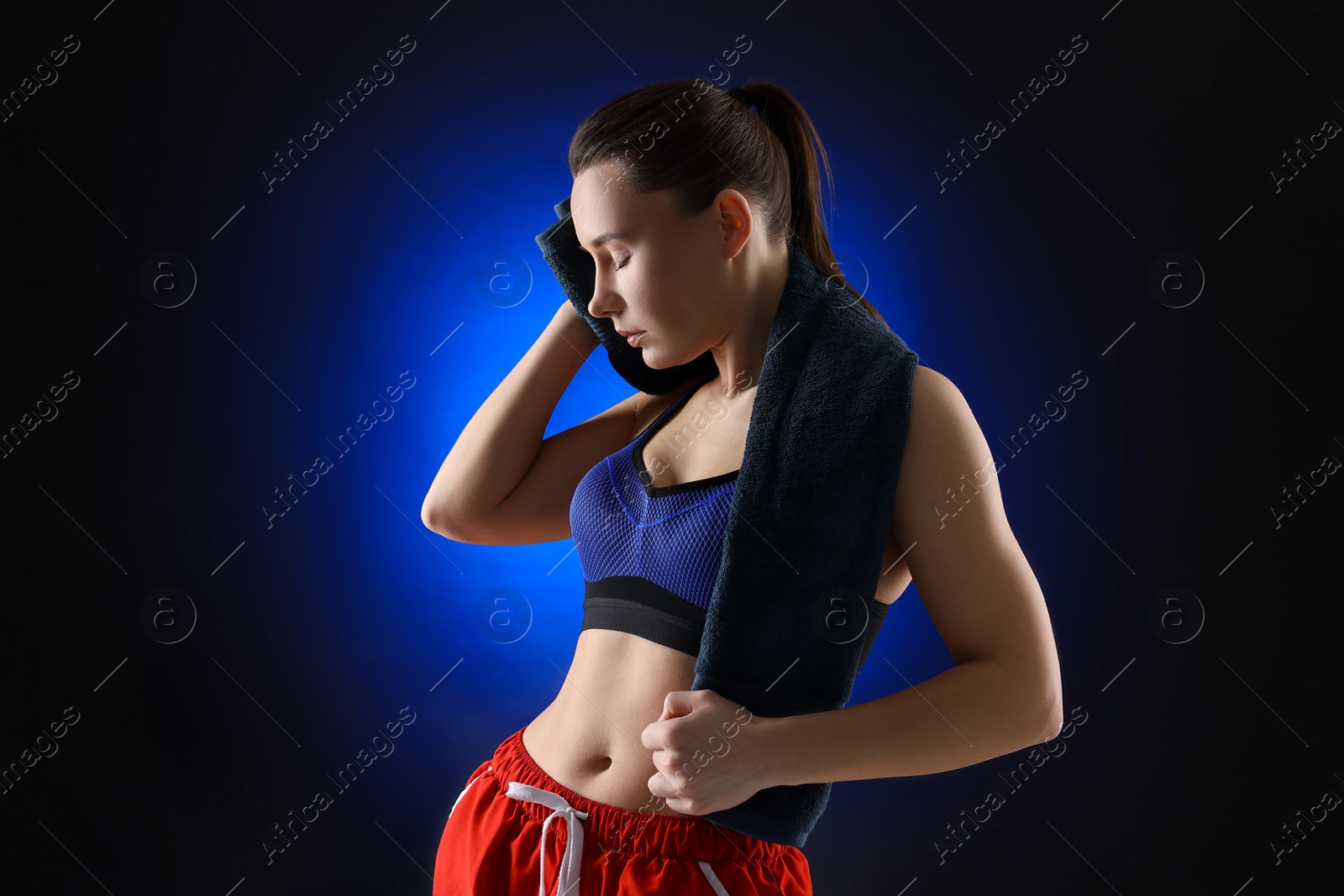 Photo of Sporty woman with terry towel on dark blue background