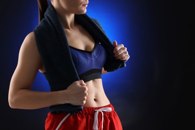 Photo of Sporty woman with terry towel on dark blue background, closeup. Space for text