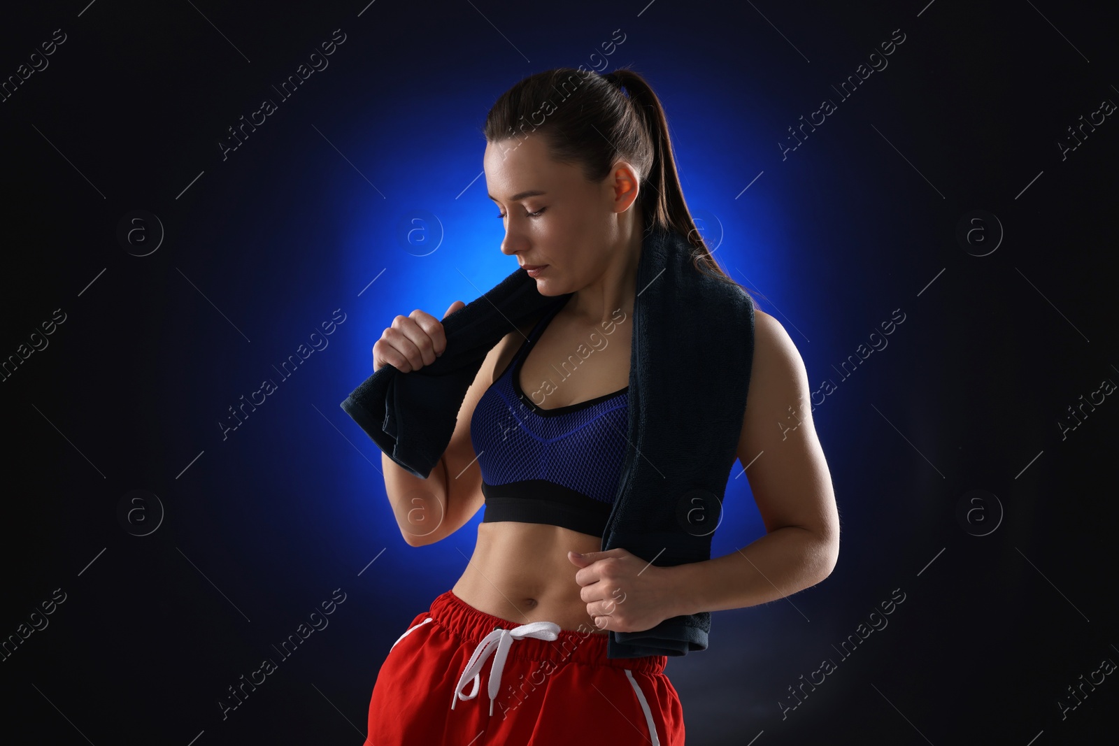 Photo of Sporty woman with terry towel on dark blue background