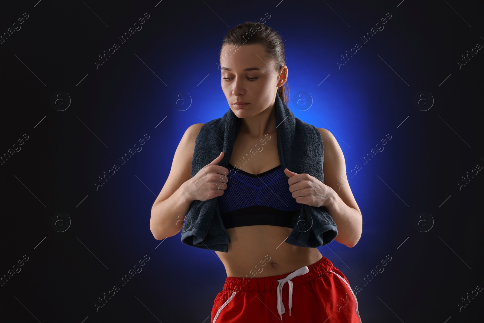 Photo of Sporty woman with terry towel on dark blue background